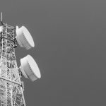 Fotografía en blanco y negro de dos antenas en una torre, destacando su estructura y diseño minimalista.